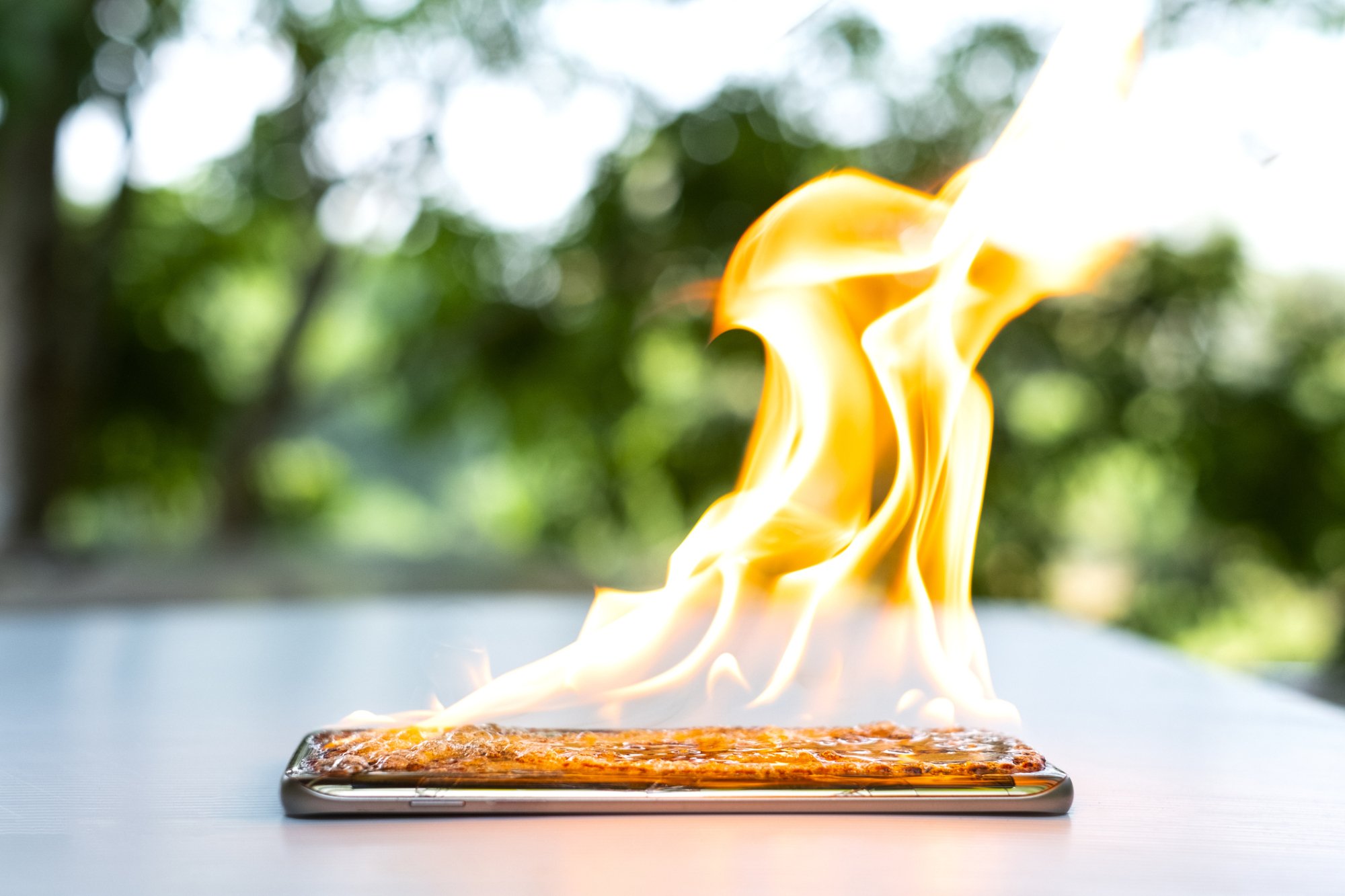 Black smartphone on white table lit on fire.