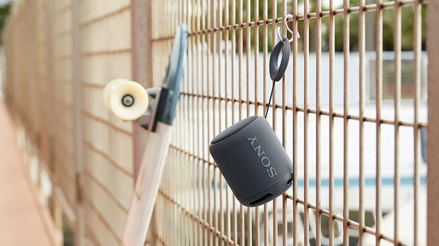 A mini portable speaker hanging from a fence