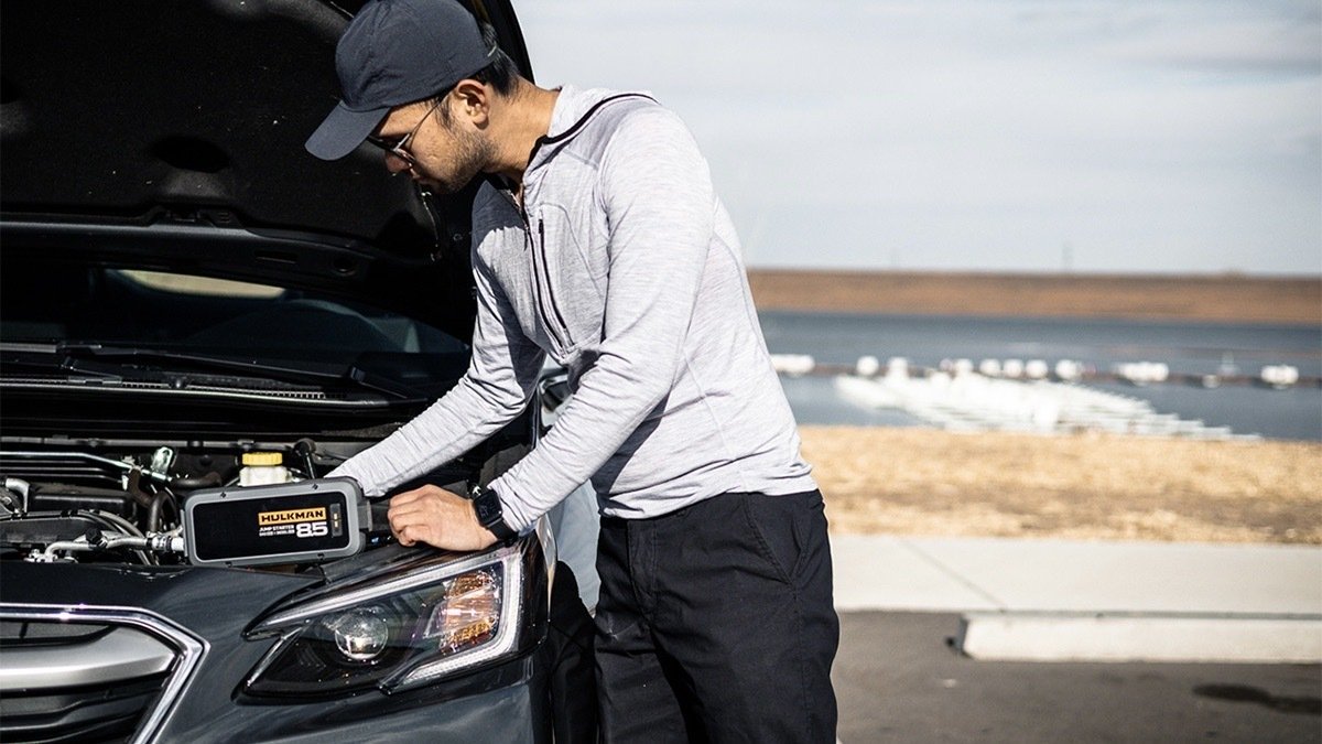 Person using a HULKMAN Alpha 85: 2000A Jump Starter to jump start their car.