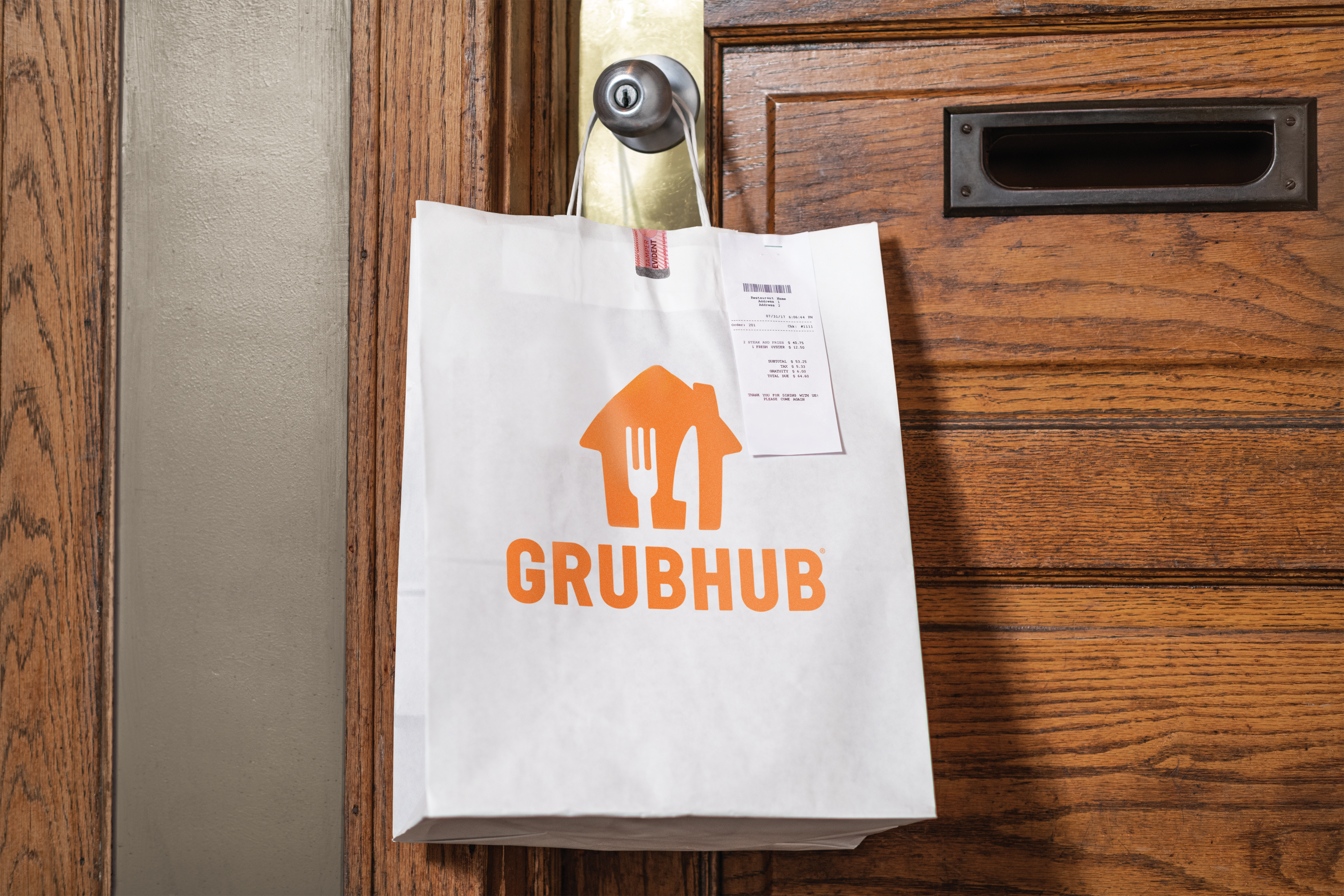 A Grubhub bag hanging from a doorknob.