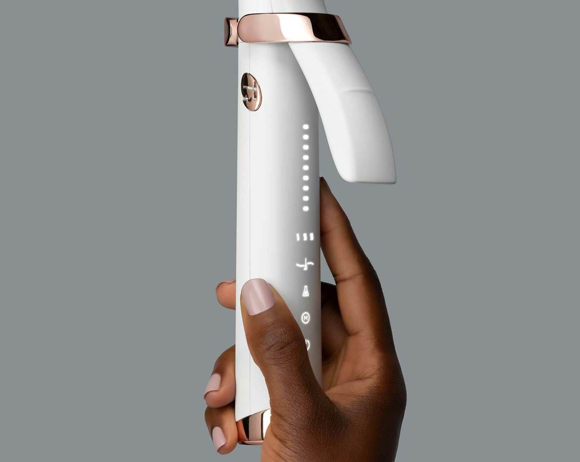 Bottom half of a white curling iron with rose gold accents being held. 