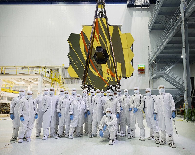 scientists standing in front of the James Webb Space Telescope