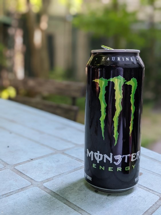 Can of Monster energy on picnic table with bokeh background