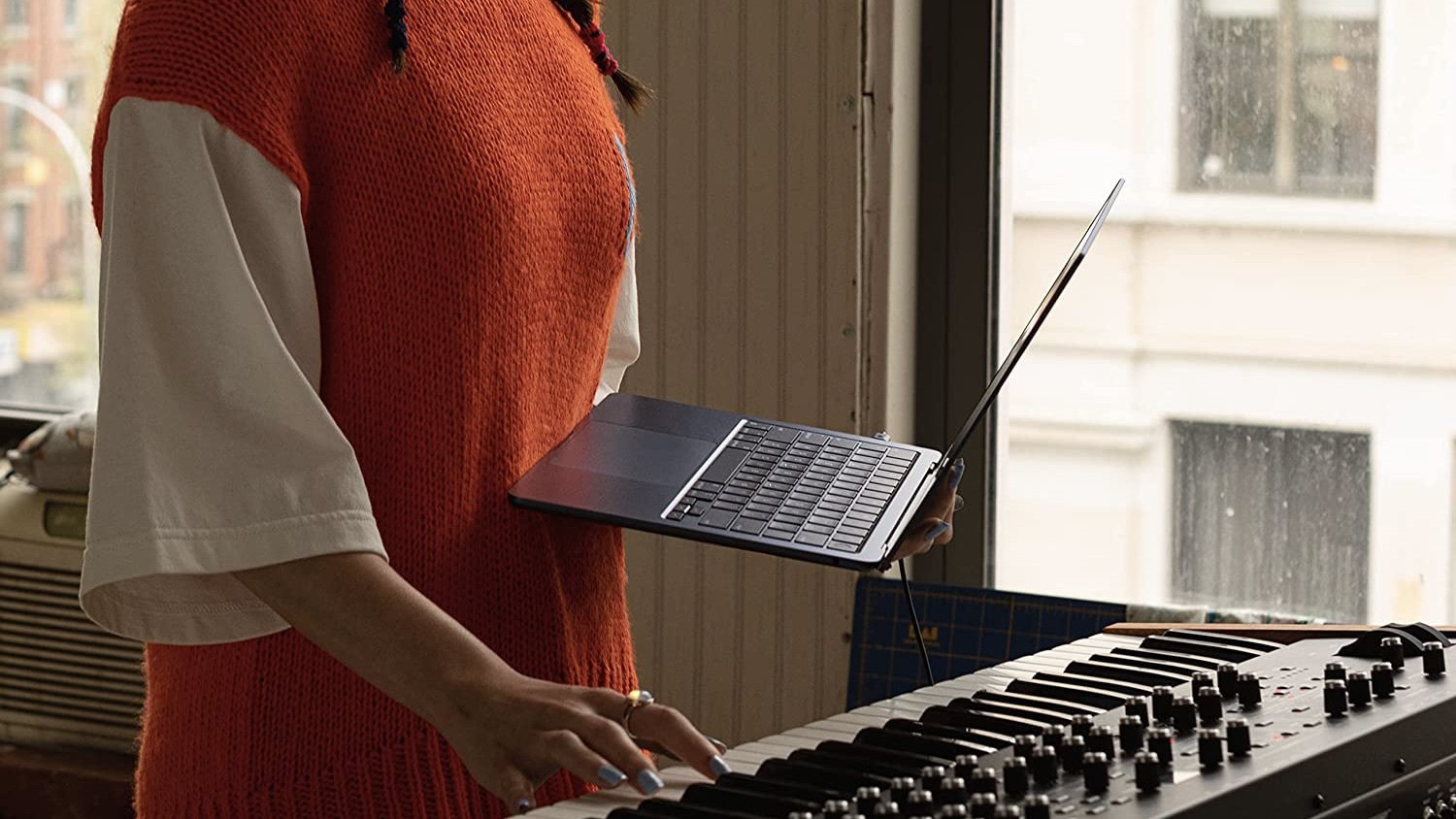 person holding macbook air in front of a piano