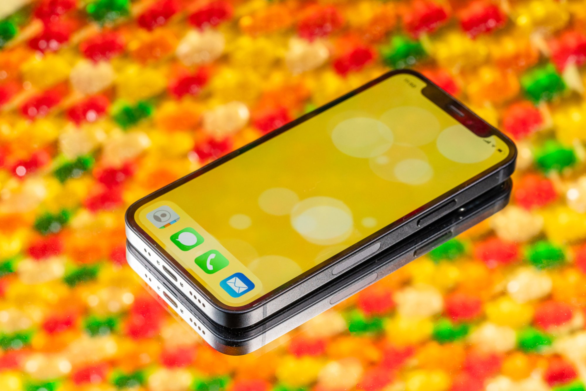 iPhone 12 mini against backdrop of multiple gummy bears