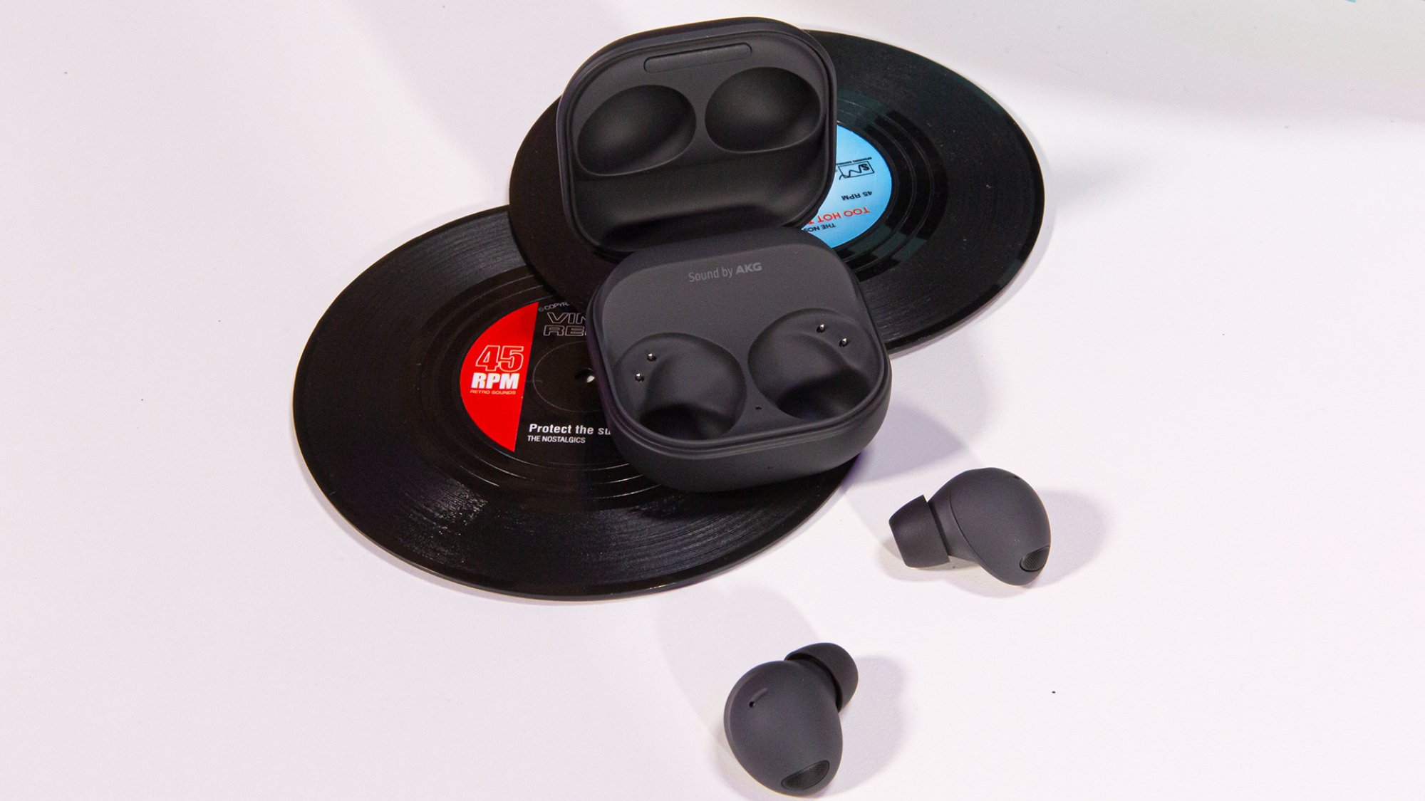 A pair of black Galaxy Buds 2 Pro earbuds sit beside an open black charging case