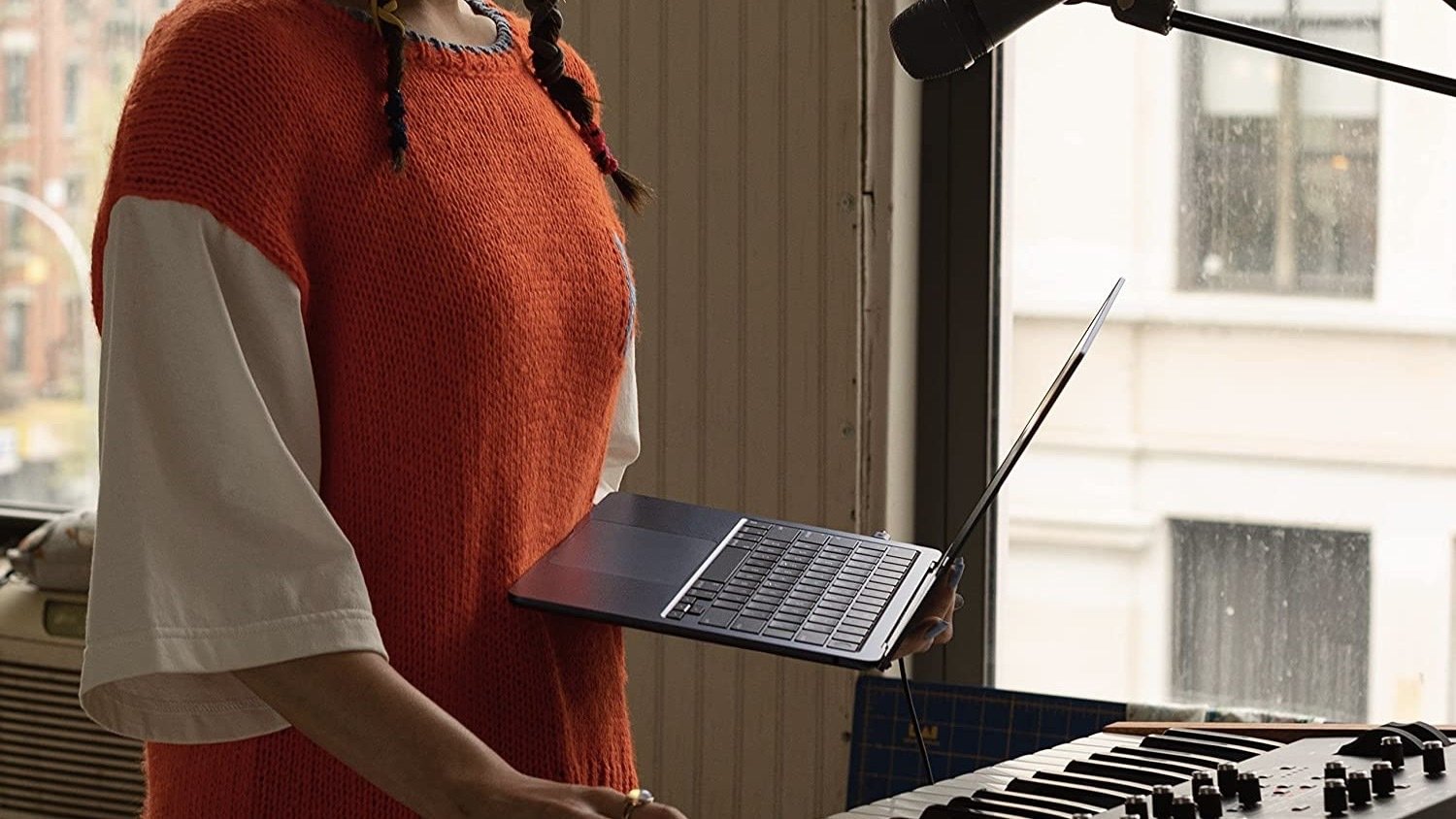 person holding macbook air and standing at a keyboard