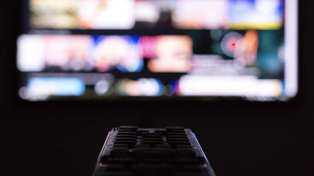 Person pointing a remote at a tv.