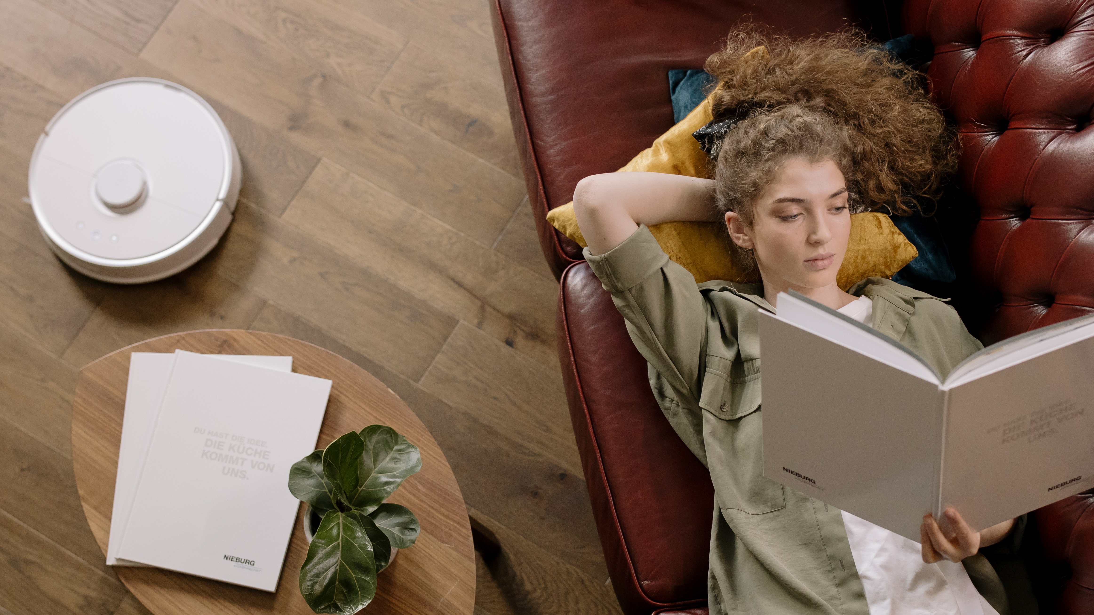 A robot vacuum at work while a woman relaxes