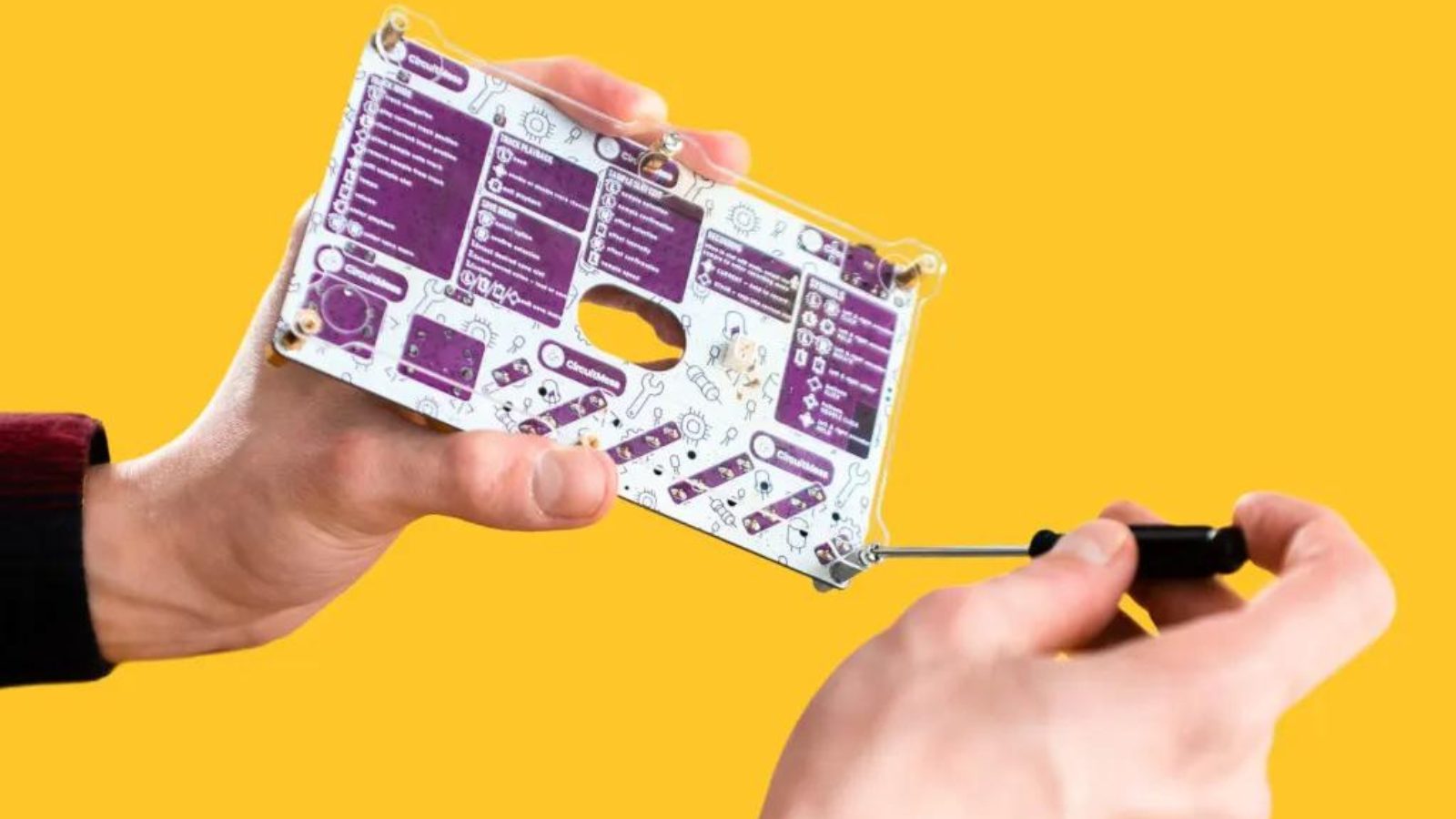 hands working on the Synthia DIY digital music sampler with yellow background