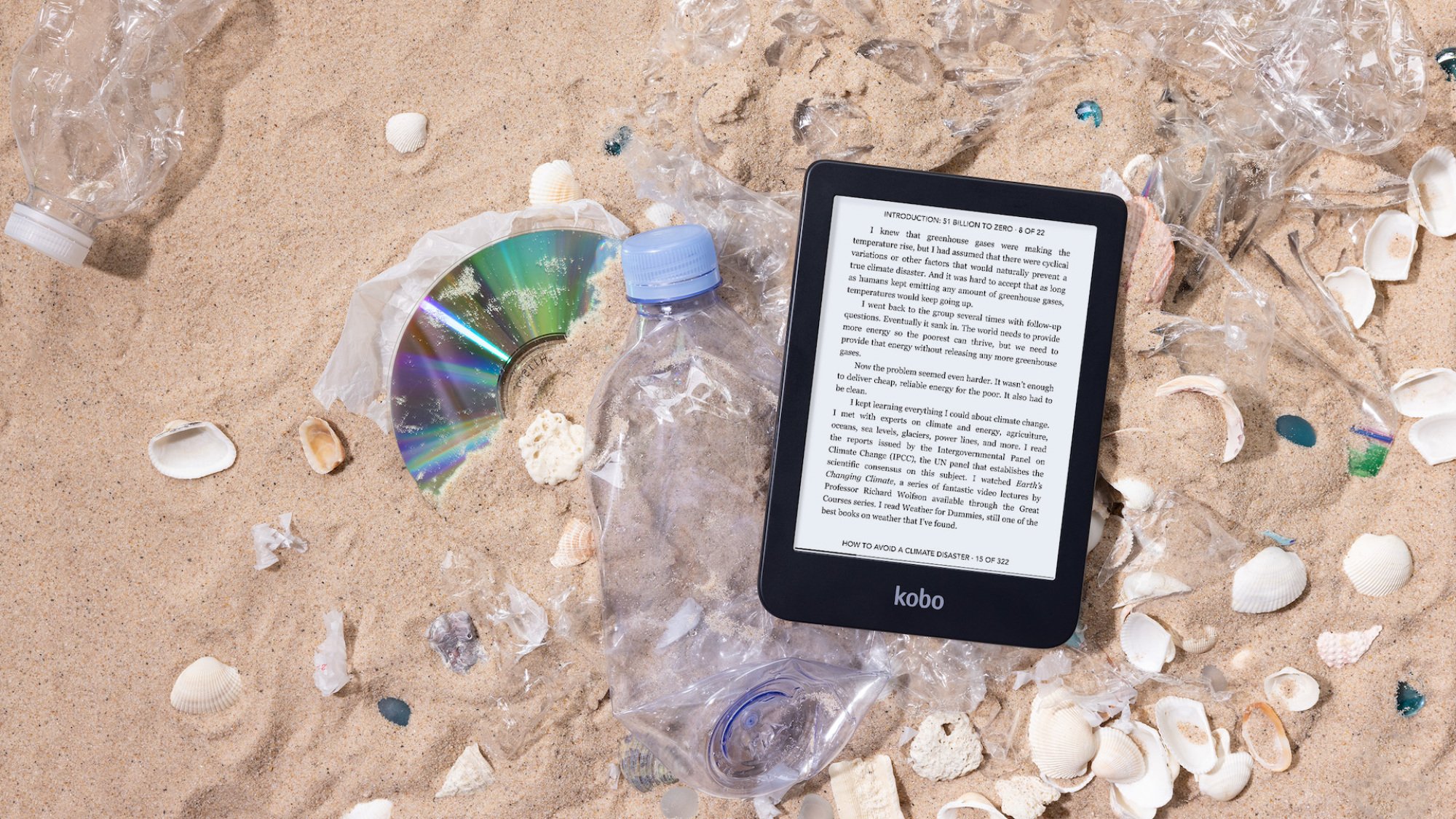 Kobo's new Clara 2E e-reader lying on sand atop various forms of plastic waste.