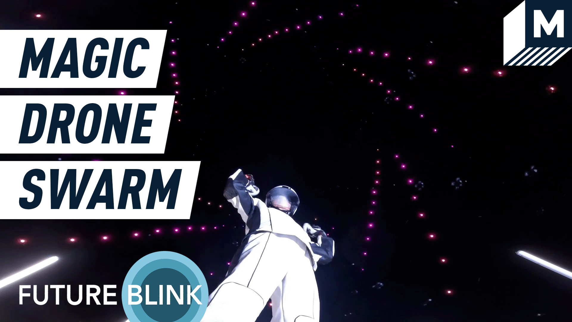 A man controlling a large swarm of colorful drones above him