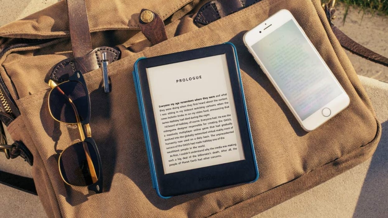 An e-reader called the Amazon Kindle is placed on a surface with some text on its display