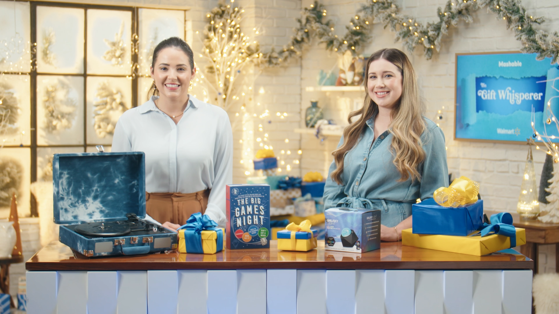 Two women standing in front of a table full of holiday deals from Walmart