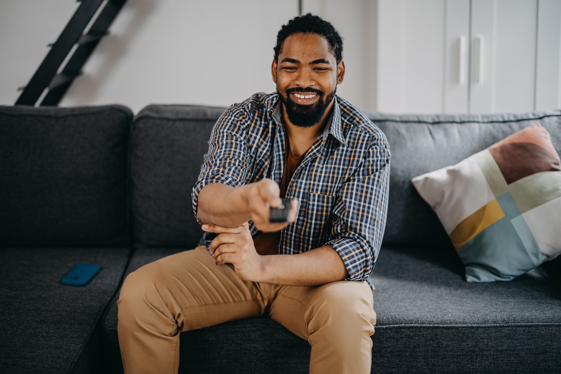 Man sitting on couch with TV remote in hand