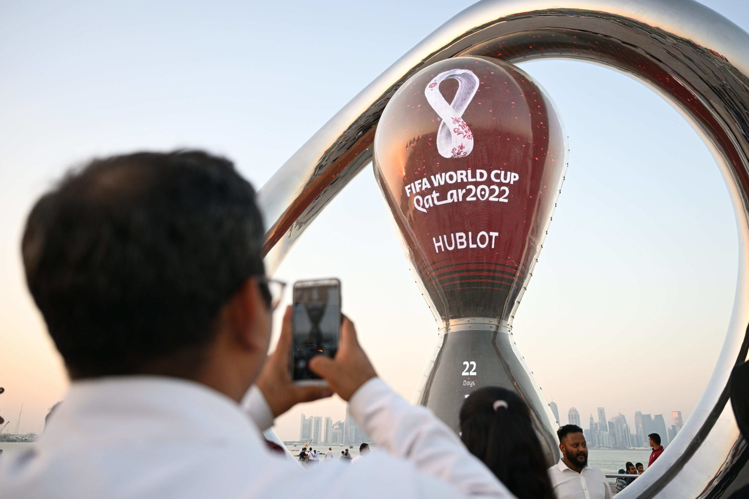 A man holds up his phone to take a picture of a giant World Cup countdown clock.