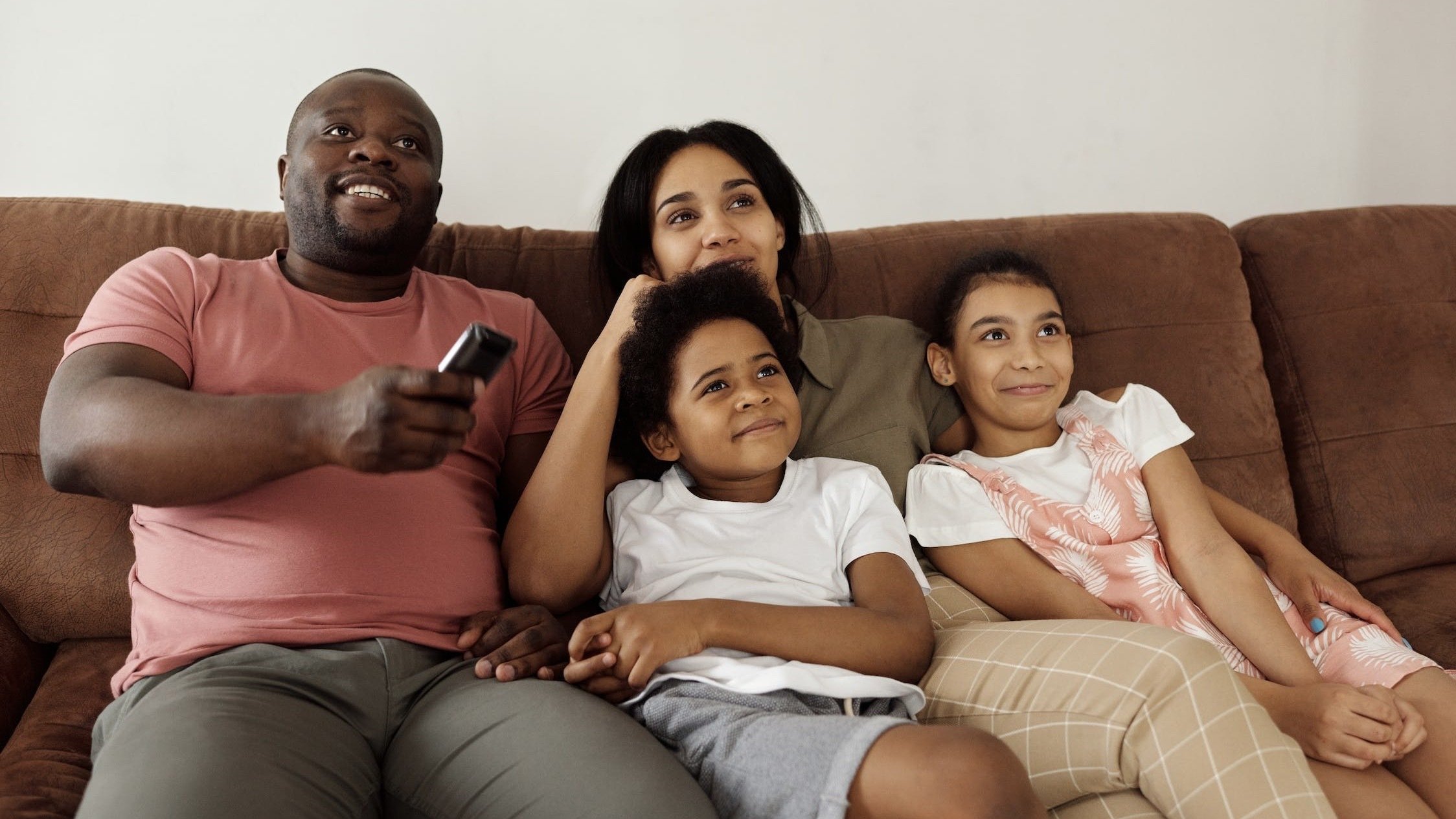 A family watching tv together on a couch.