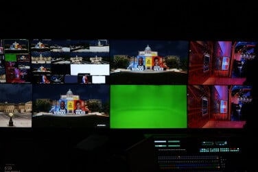 A groups of screens in a dark room. One if completely green, the other shows the Capitol.