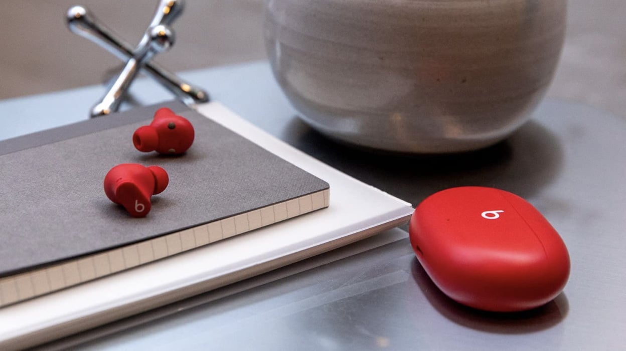 Red Beats Studio Buds on a desk on top of notebooks