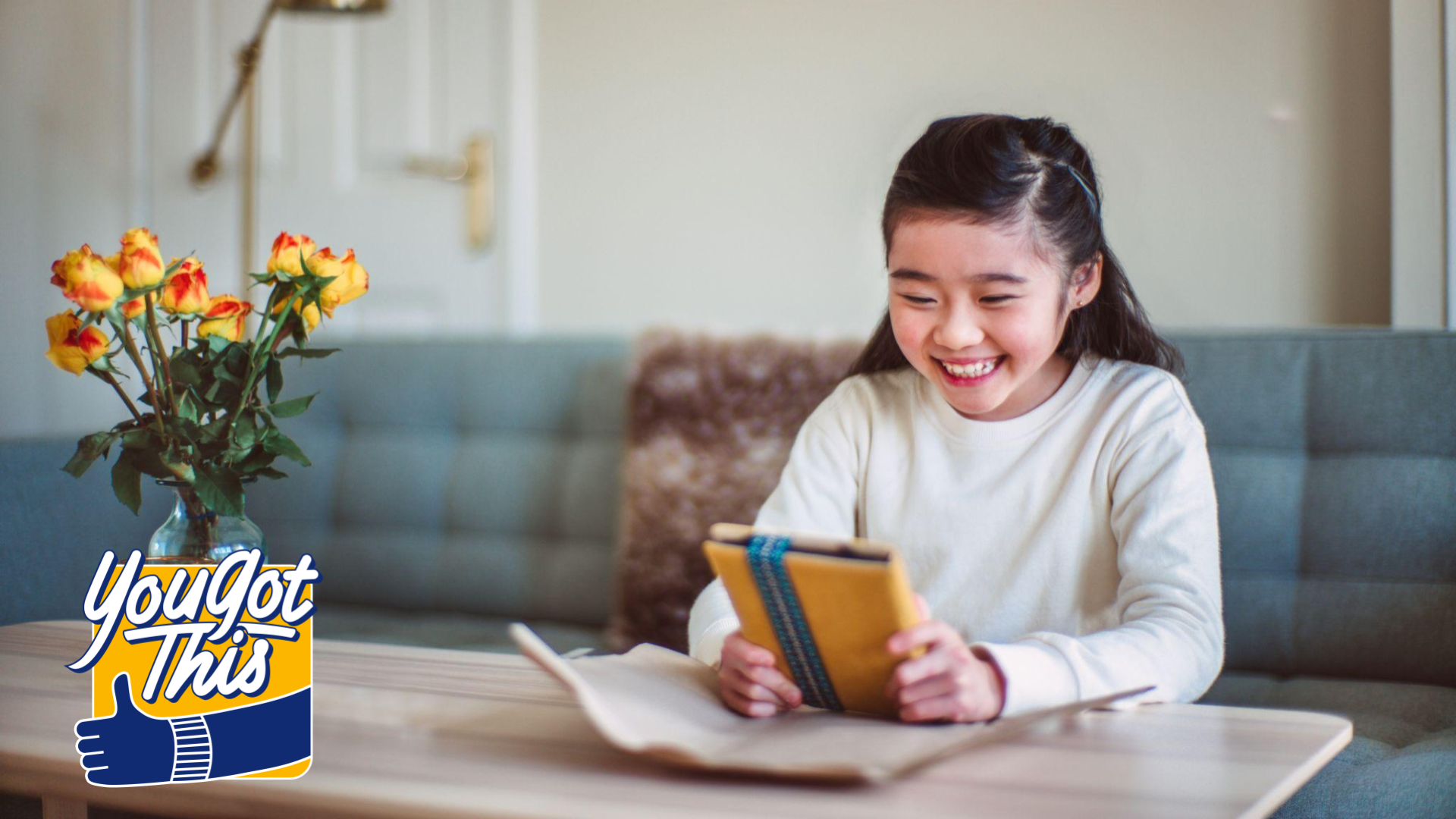 young person sits at coffee table opening a tablet gift