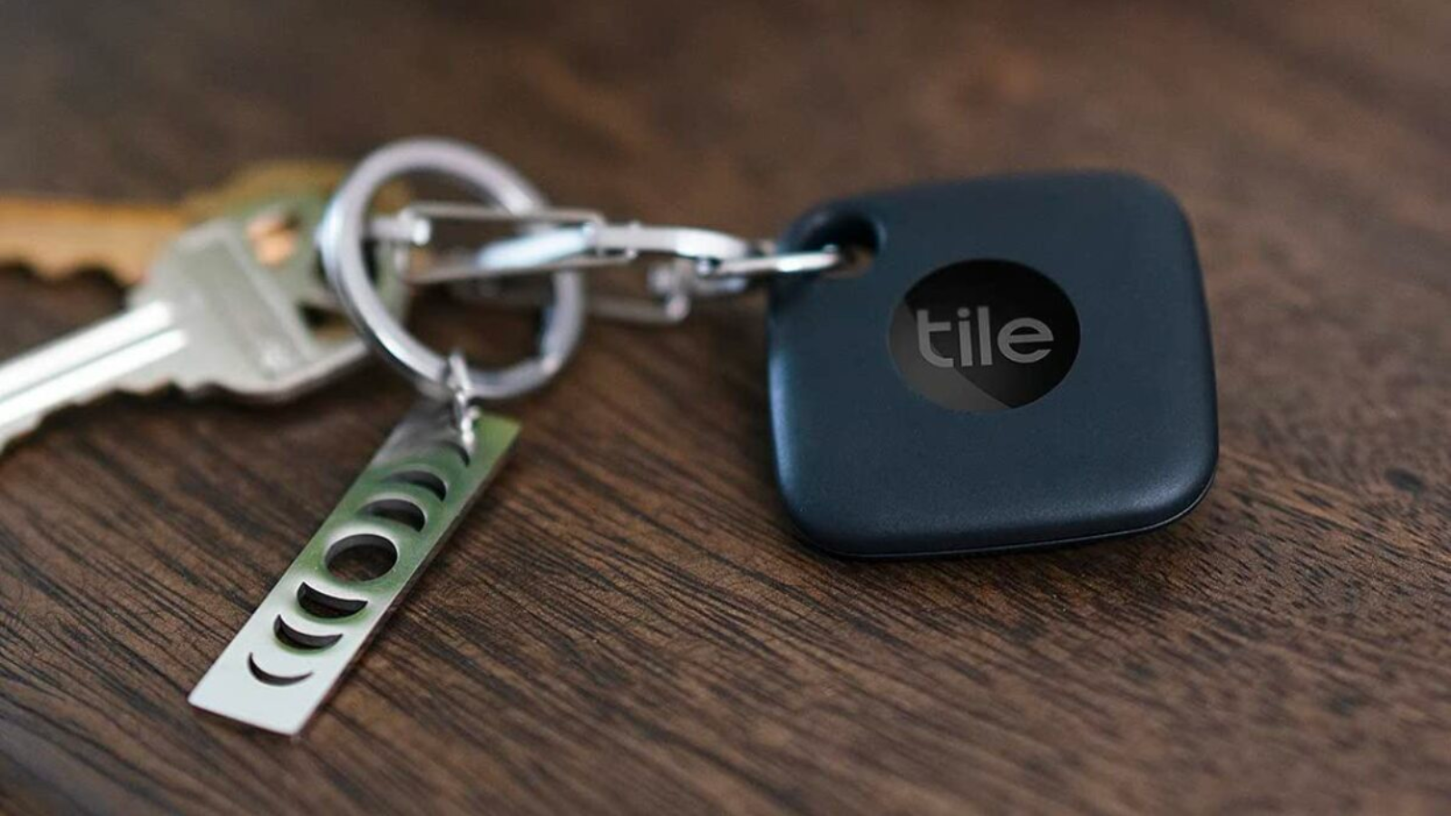 Tile tracker attached to keychain on wooden surface
