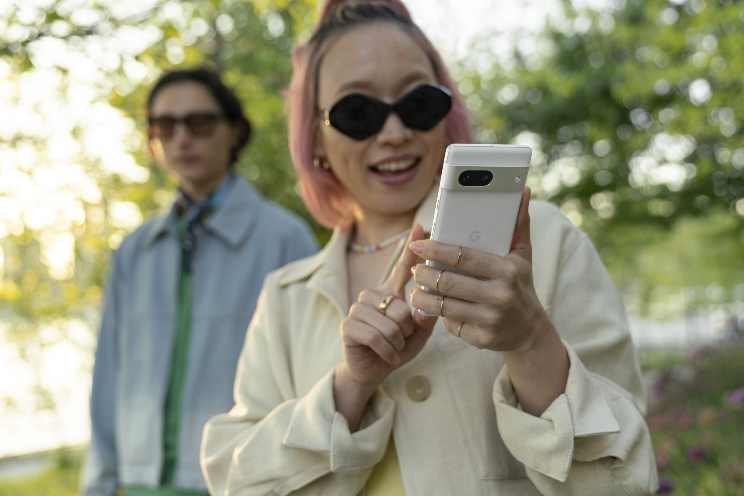woman outdoor smiling and looking at Pixel 7 in