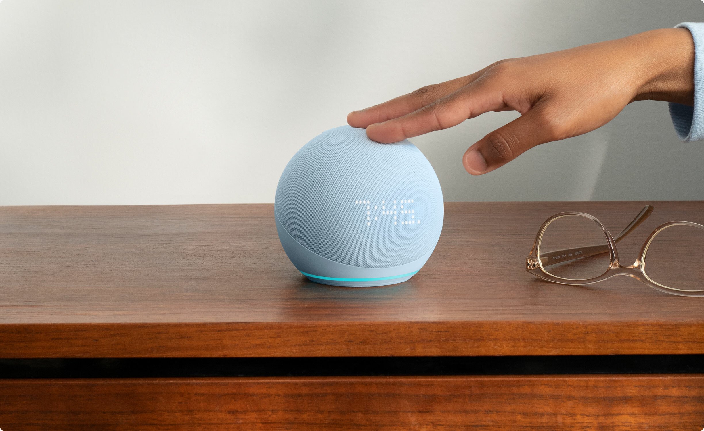 A person is touching the Echo Dot 5 smart speaker