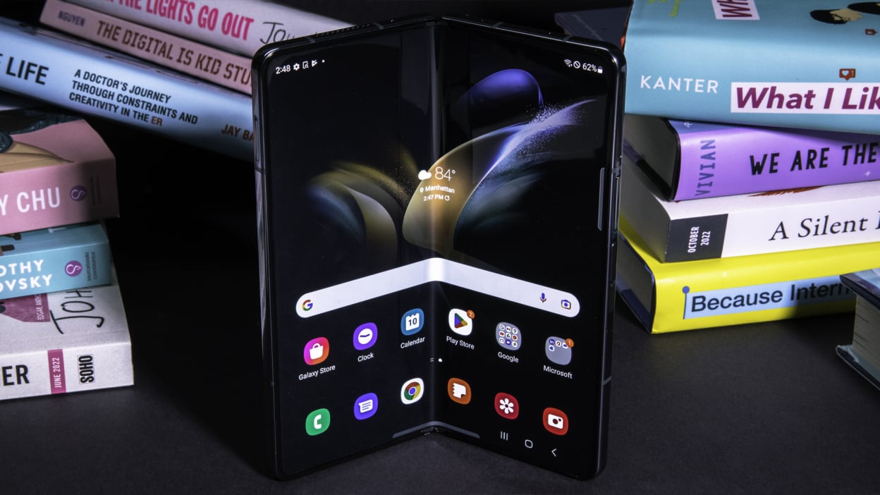 A Samsung Galaxy Z Fold4 is lying in front of a pile of books