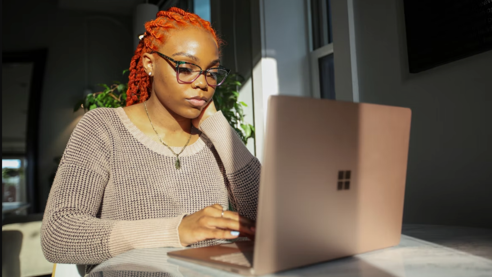 woman in tan sweater using computer