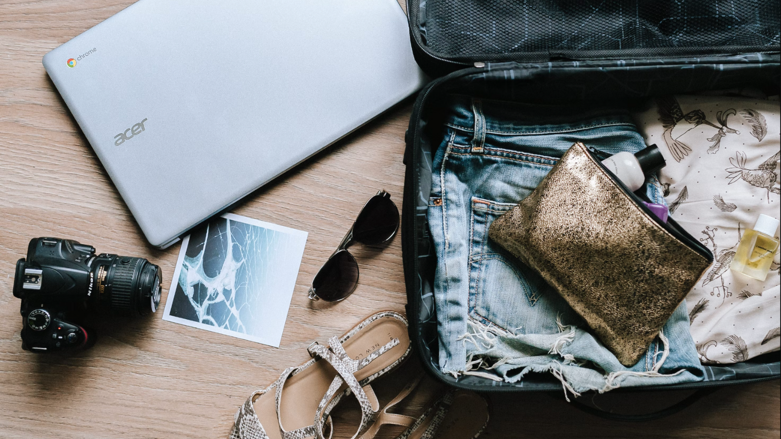 suitcase, camera, shoes, and computer on floor for packing