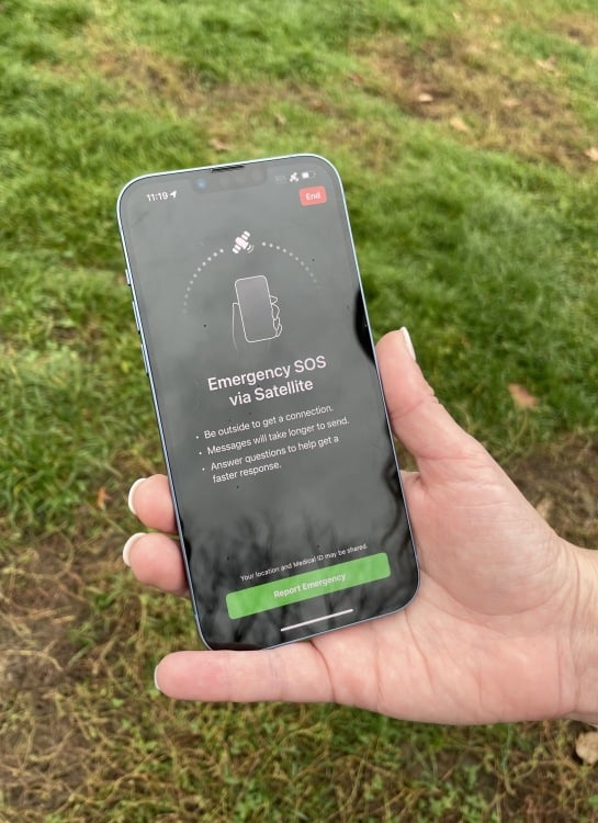 hand holding an iPhone 14 showing emergency sos via satellite