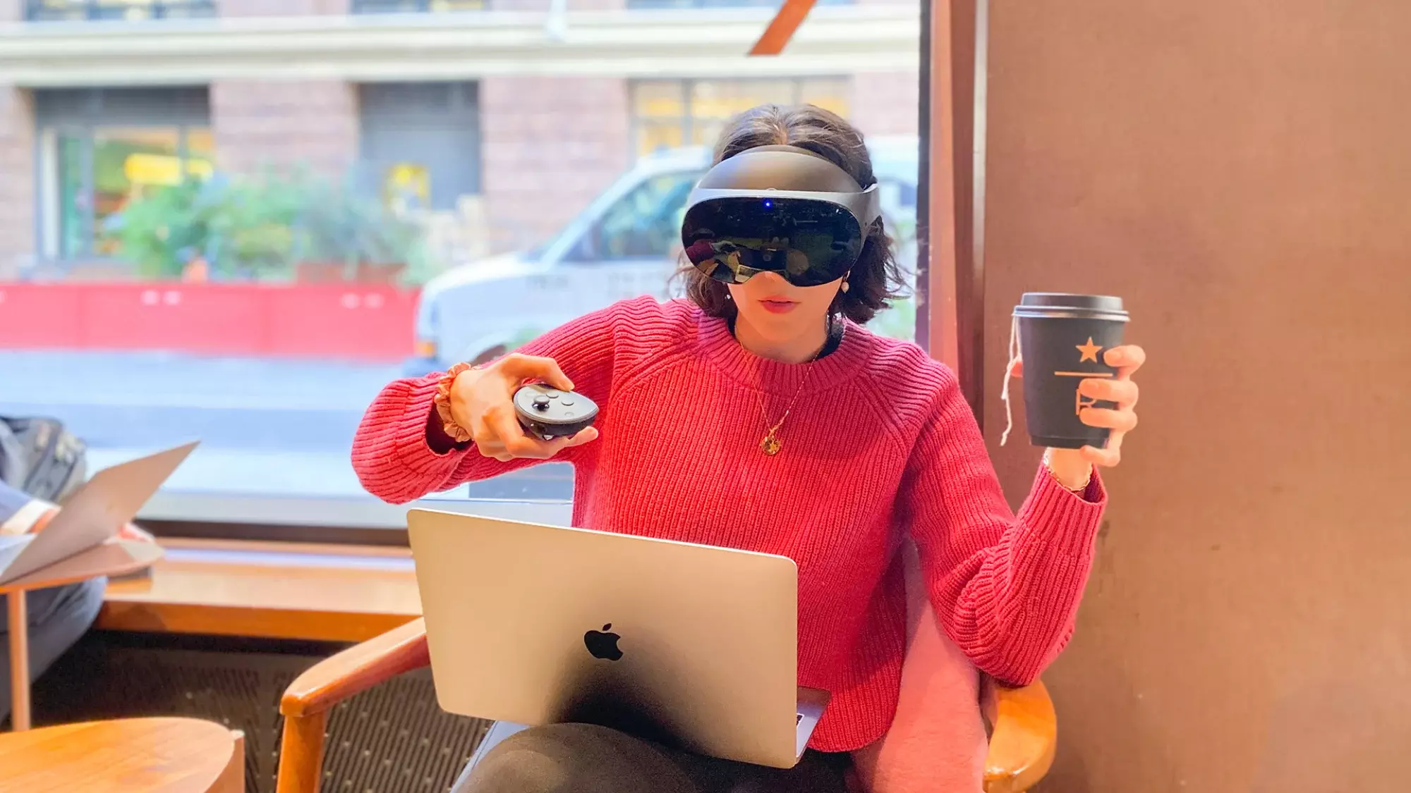Meta Quest Pro user wearing headset inside Starbucks with laptop on lap