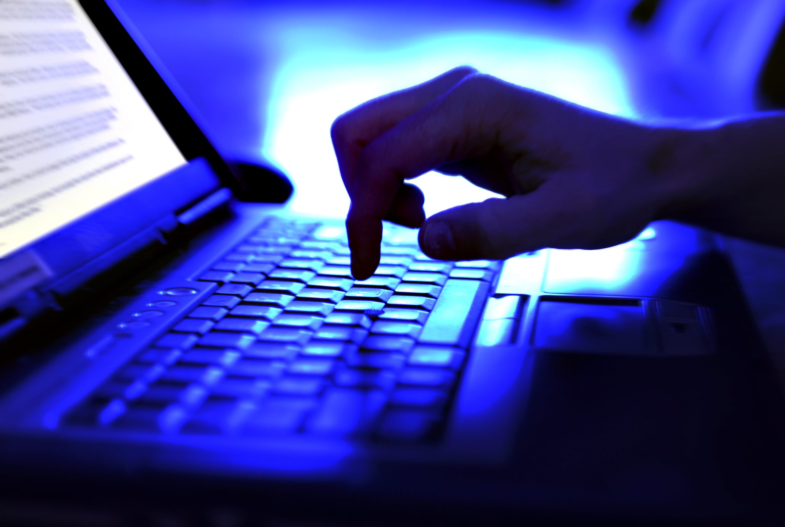 A closeup of a hand typing on a laptop keyboard.