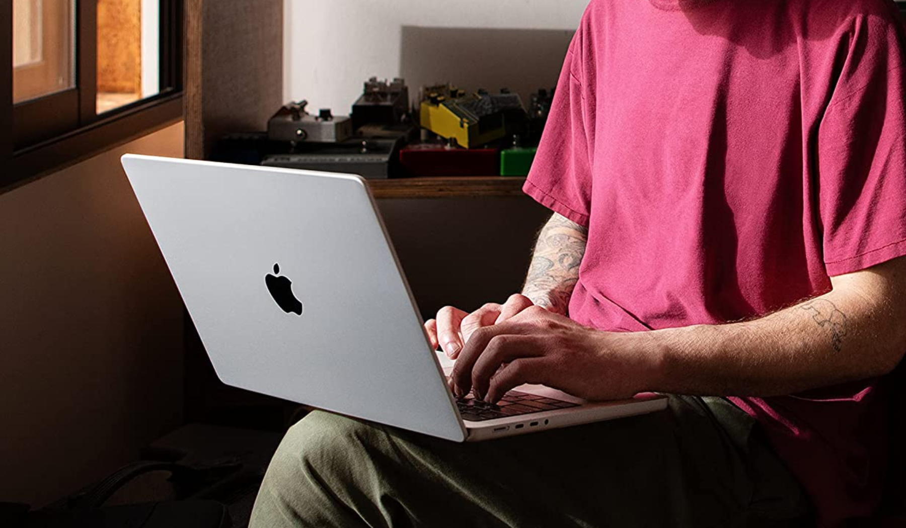 Person holding MacBook Pro on lap and typing