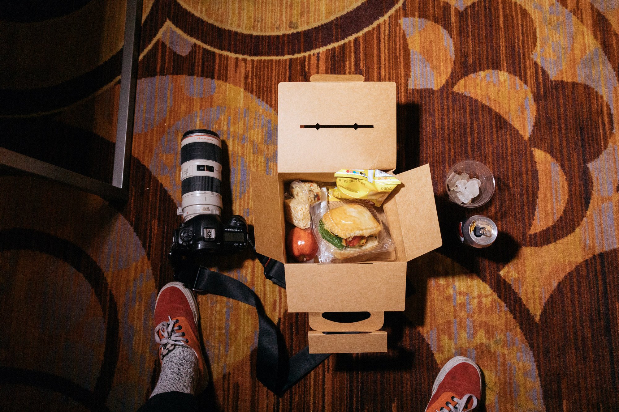 Lunch on floor next to camera and shoes