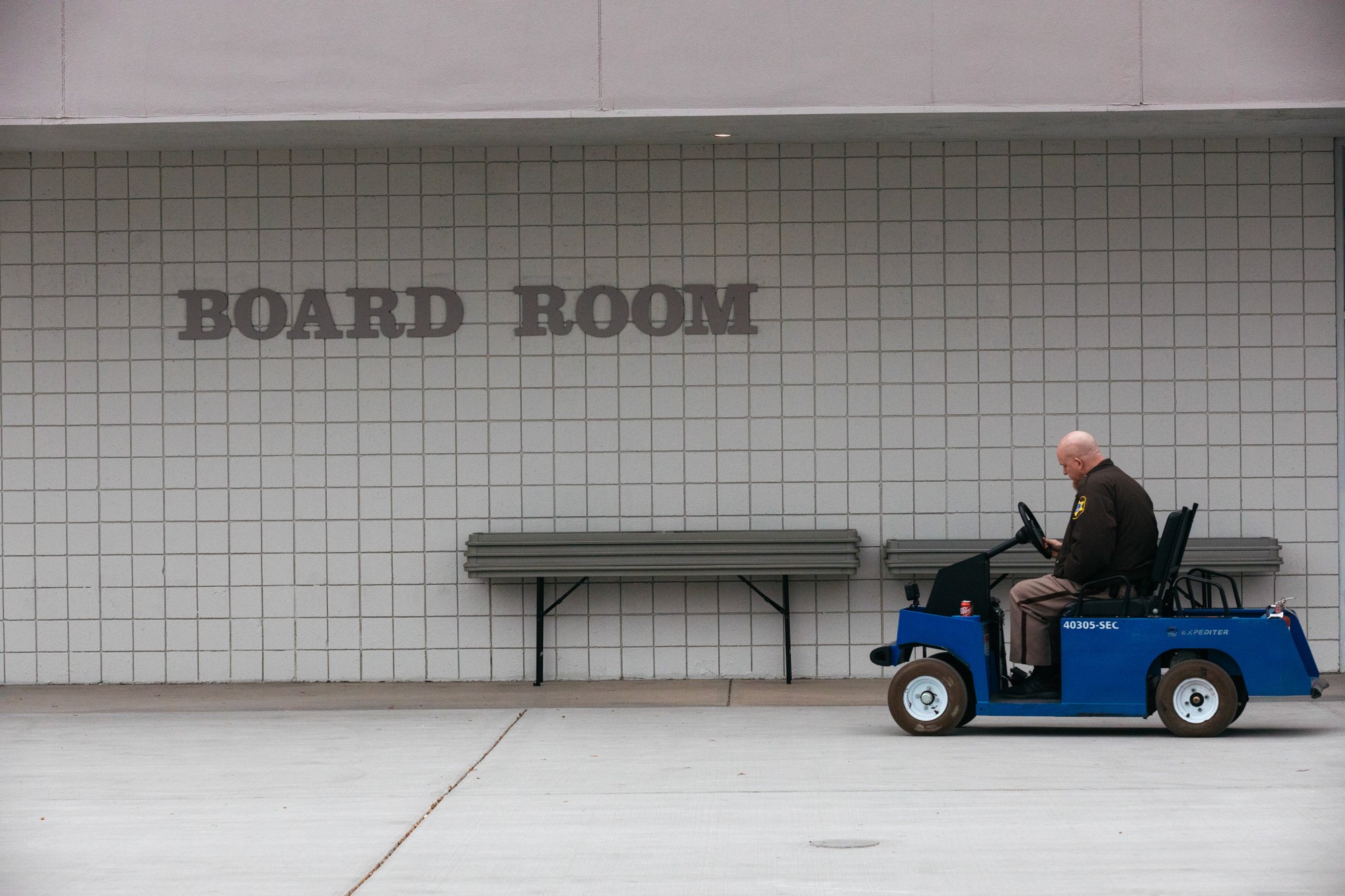 Security guard resting on go cart in front of board room sign