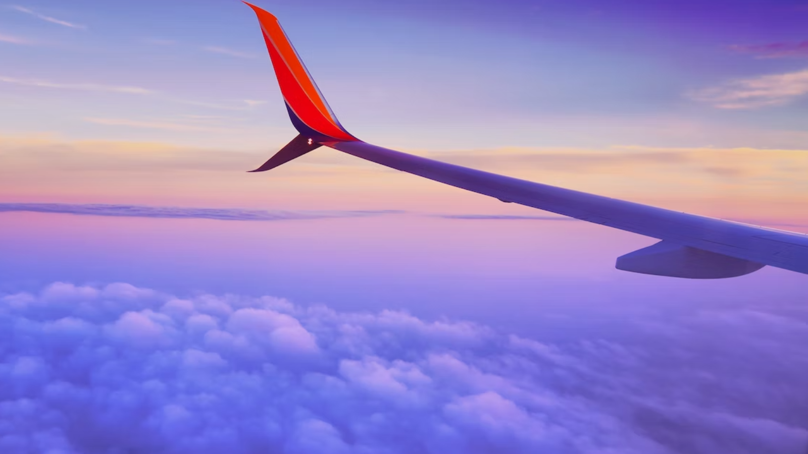 wing of plane flying above clouds