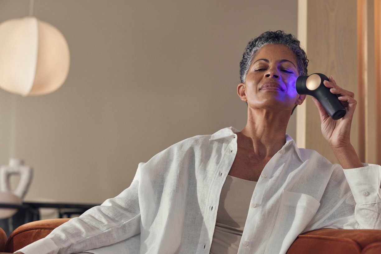 woman sitting on couch and using theraface pro with closed eyes