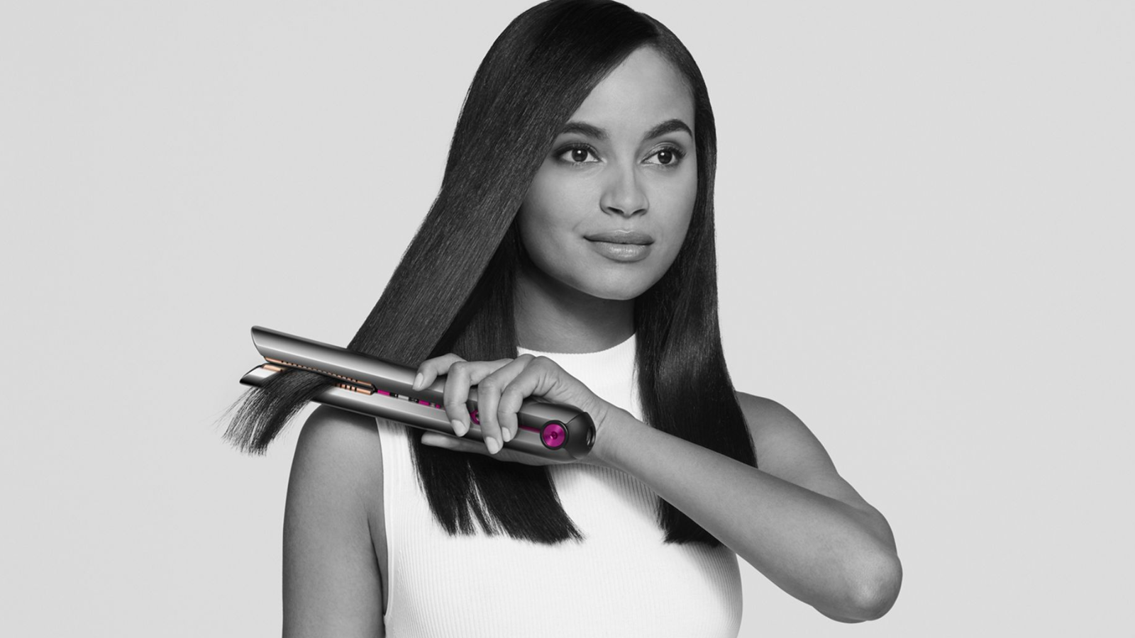 a black and white image of a woman using a dyson corrale to straighten her hair