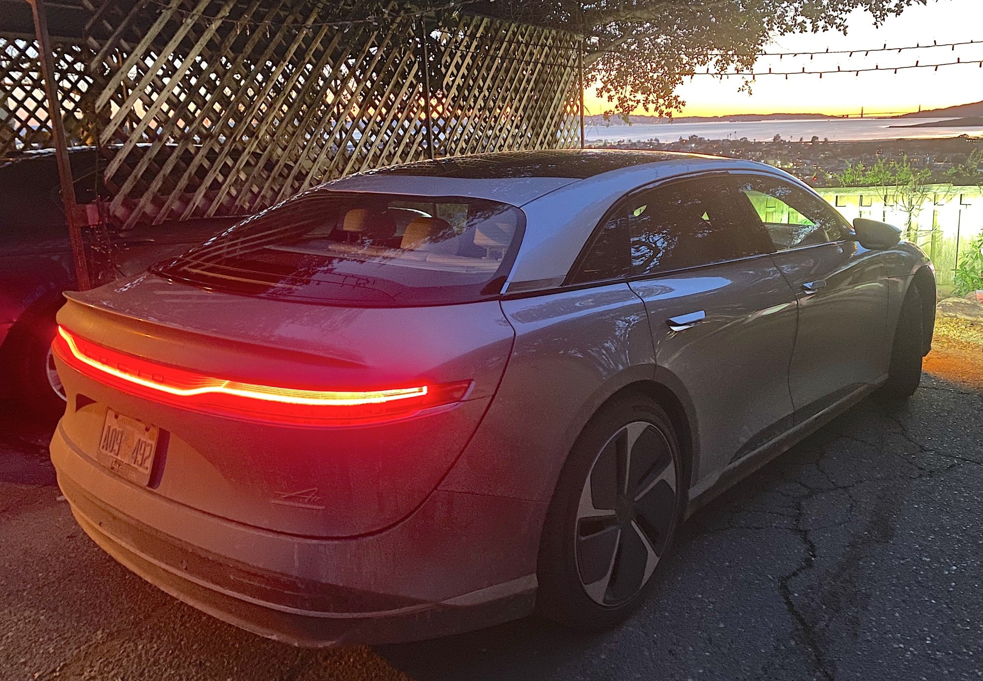 The Lucid Air at dusk from behind with a red strip of LEDs, looking over the Bay Area
