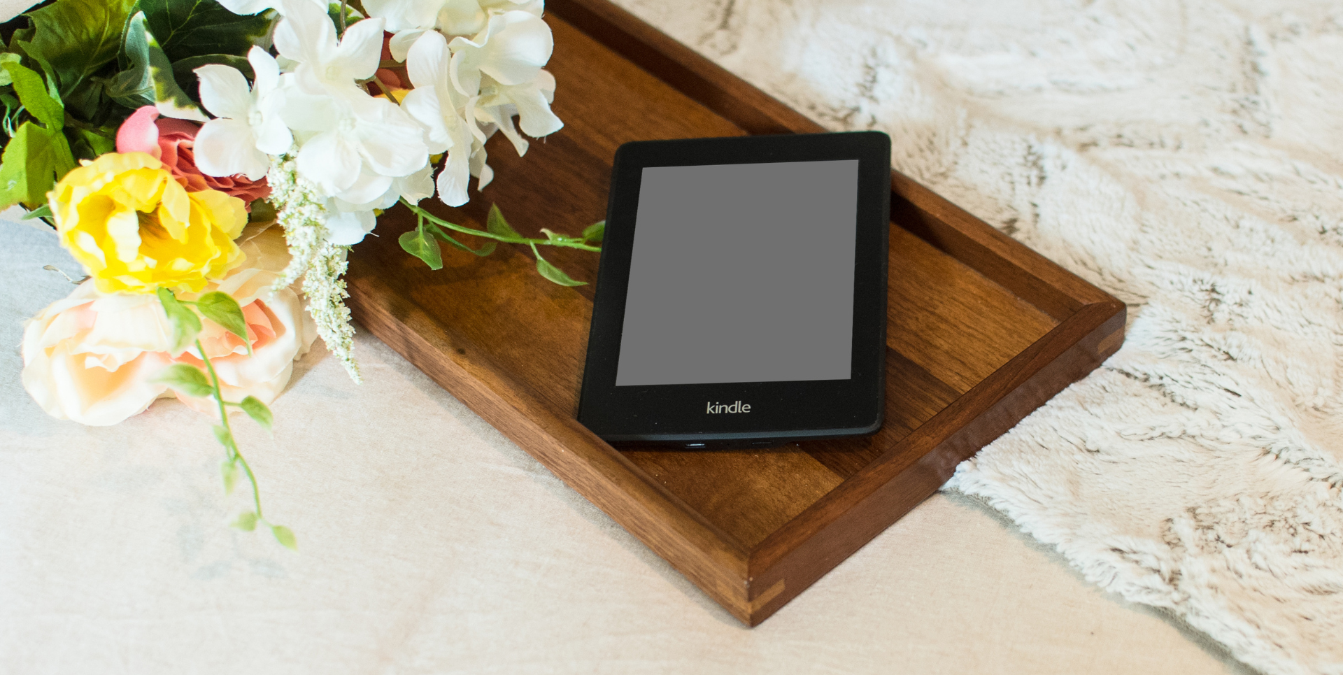 Kindle e-readr sitting on a wooden breakfast tray 