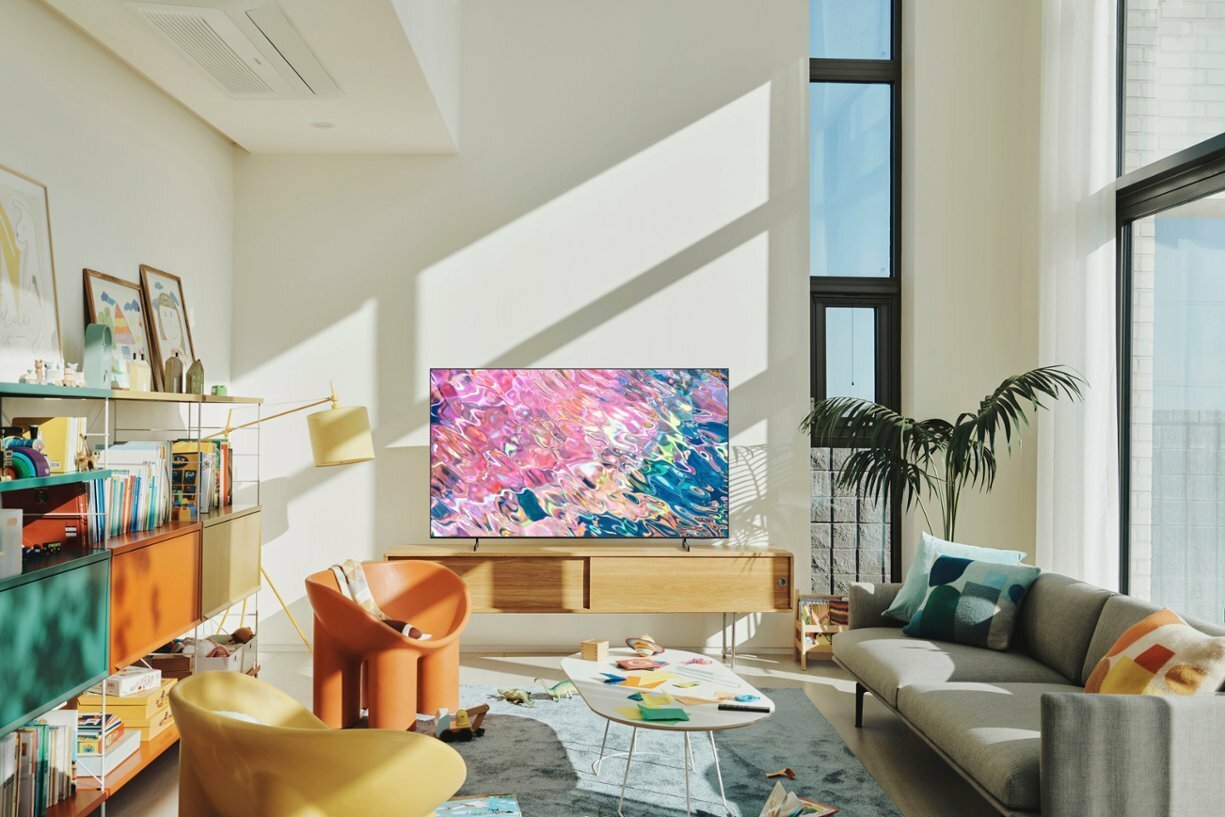 Samsung TV with colorful water screensaver on TV stand in sunlit room