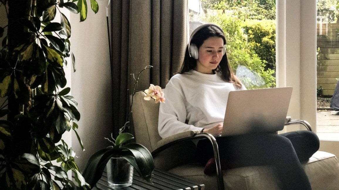 woman sitting in living room on her laptop wearing silver bose 700 headphones