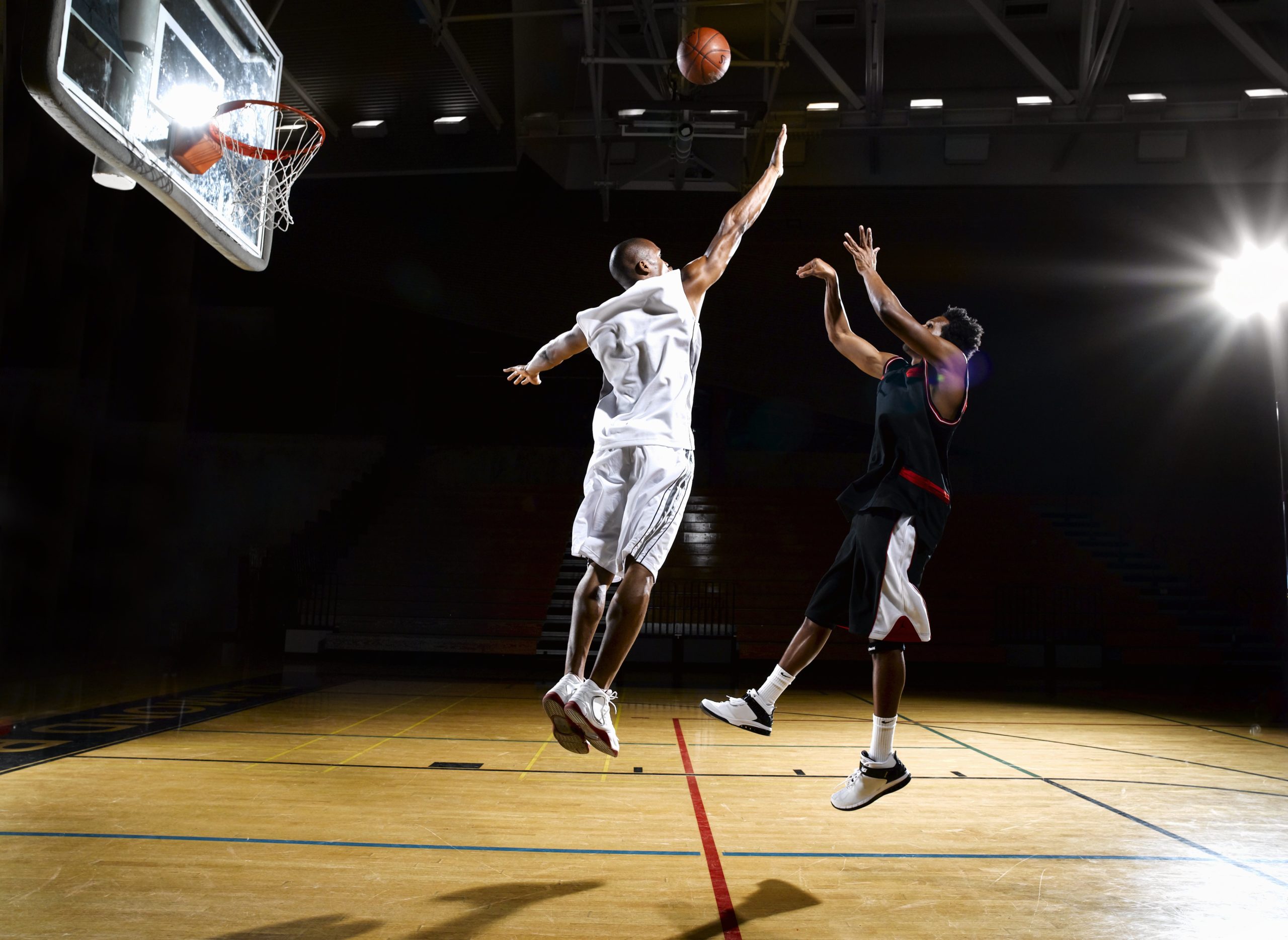 Basketball player shooting fade away while opponent blocks shot 