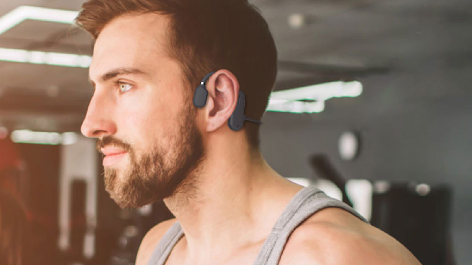 man wearing open ear headphones in gym