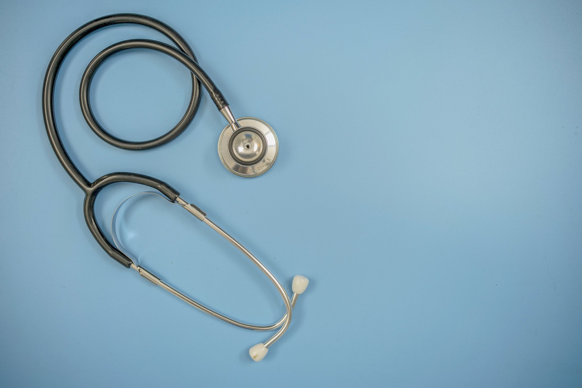 A black stethoscope on a light blue background. 