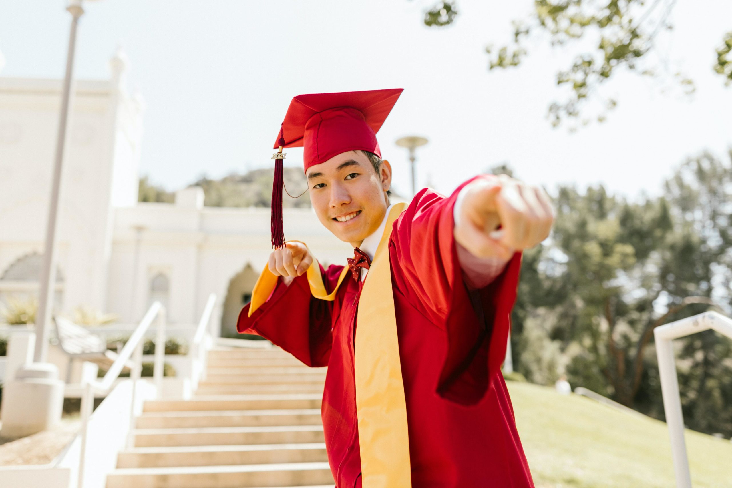 a man in red academic regalia smiling while wearing mortarboard