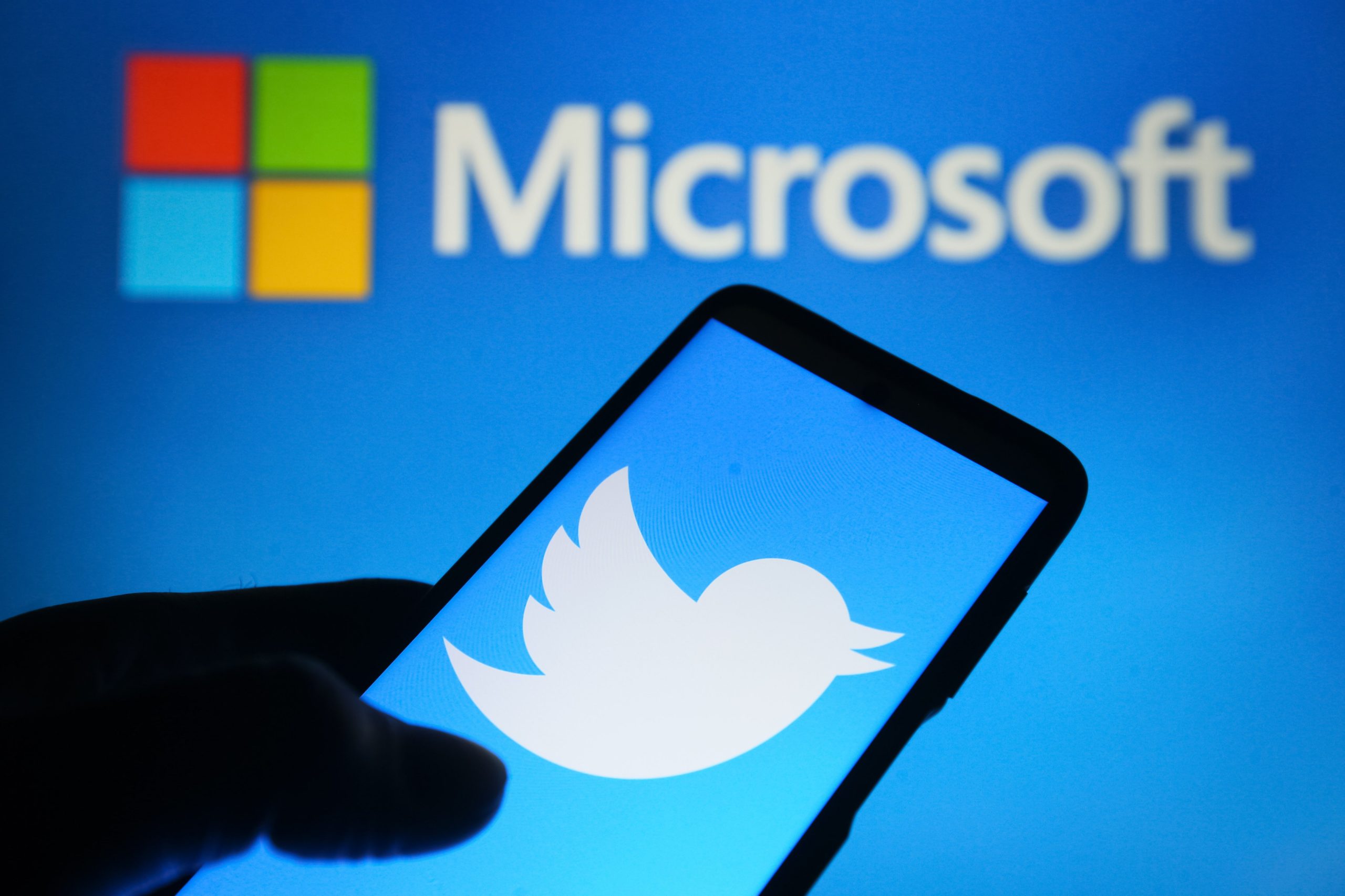 Microsoft logo hovering above Twitter logo on a mobile device