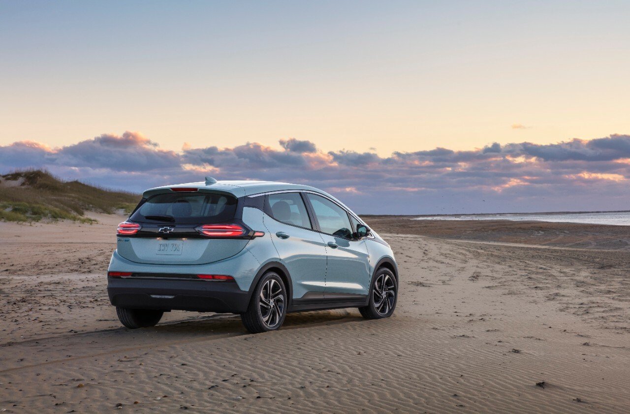 The 2022 Chevrolet Bolt EV, parked on a beach as the sun sets.