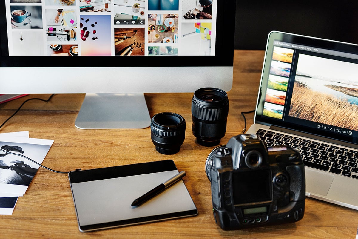 desktop with camera, computer, keyboard, tablet, and stylus pen